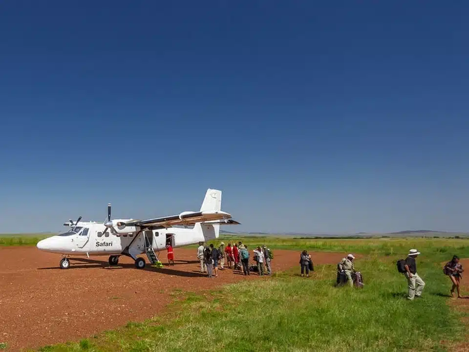 Petit avion de safari sur une piste en brousse, transportant des voyageurs vers un parc national de Tanzanie